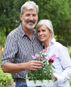 Man and woman with full smiles after dental implant osseointegration and abutment placement