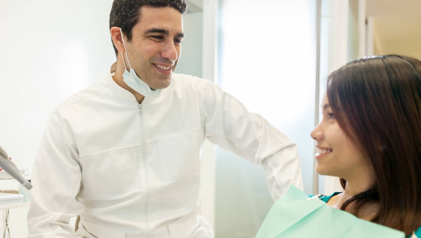 Smiling dentist talking to dental patient