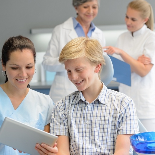 Young dental patient talking to team member during dental checkup and teeth cleaning visit