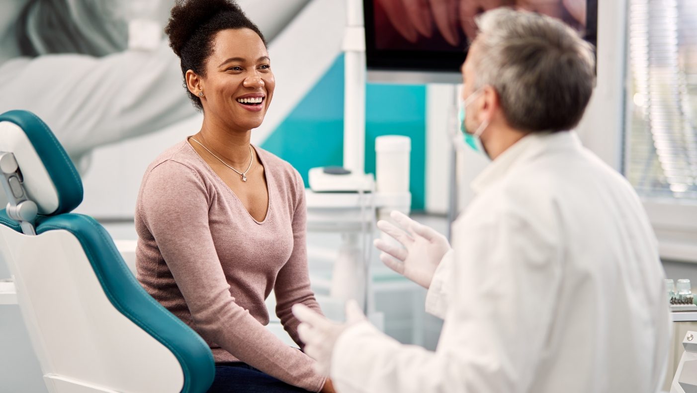 Woman laughing with dentist during dental checkup and teeth cleaning visit