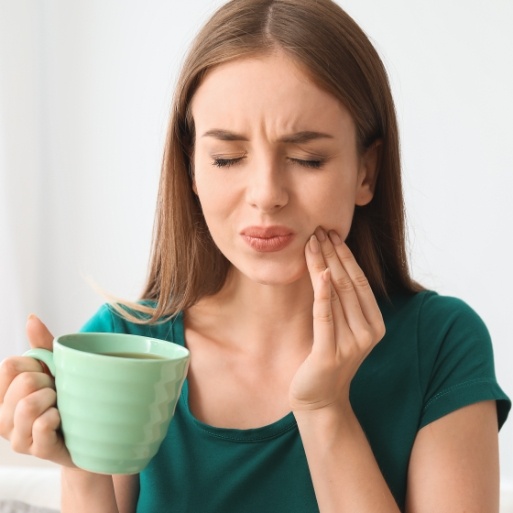 Woman in need of emergency dentistry holding cheek in pain