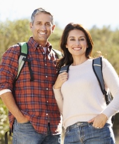 Man and woman sharing healthy smiles after dental implant surgery