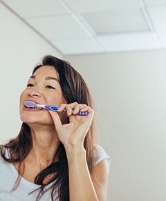 Woman brushing her teeth in bathroom