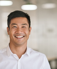 Man in white button up shirt smiling in office