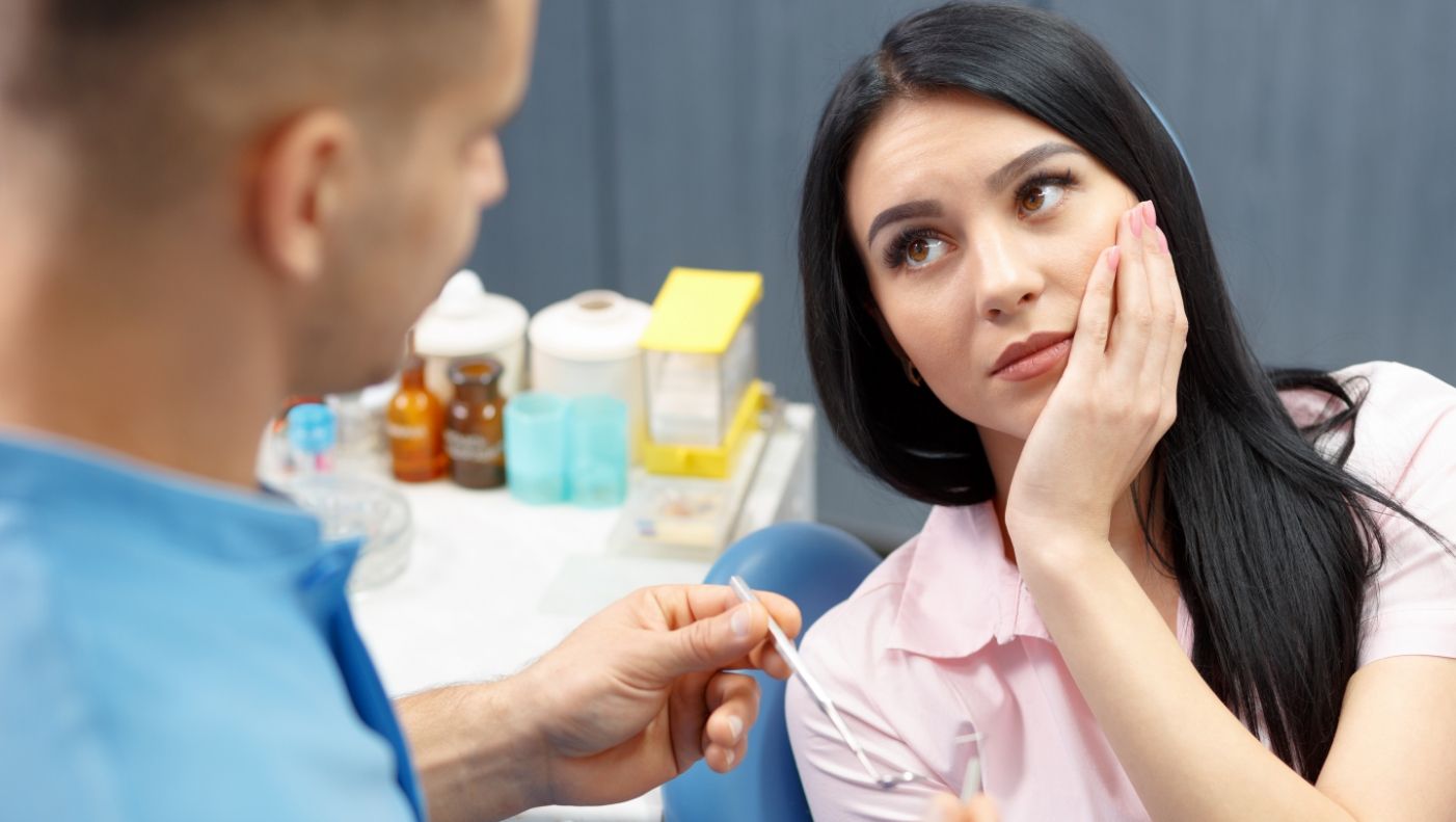 Woman in need of root canal therapy holding cheek in pain