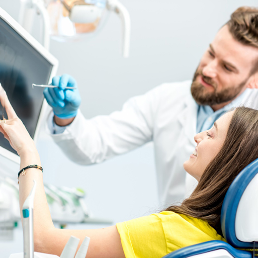 Patient and dentist smiling while reviewing X-ray on screen