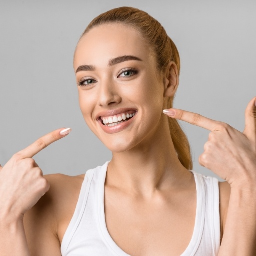 Woman pointing to smile after teeth whitening